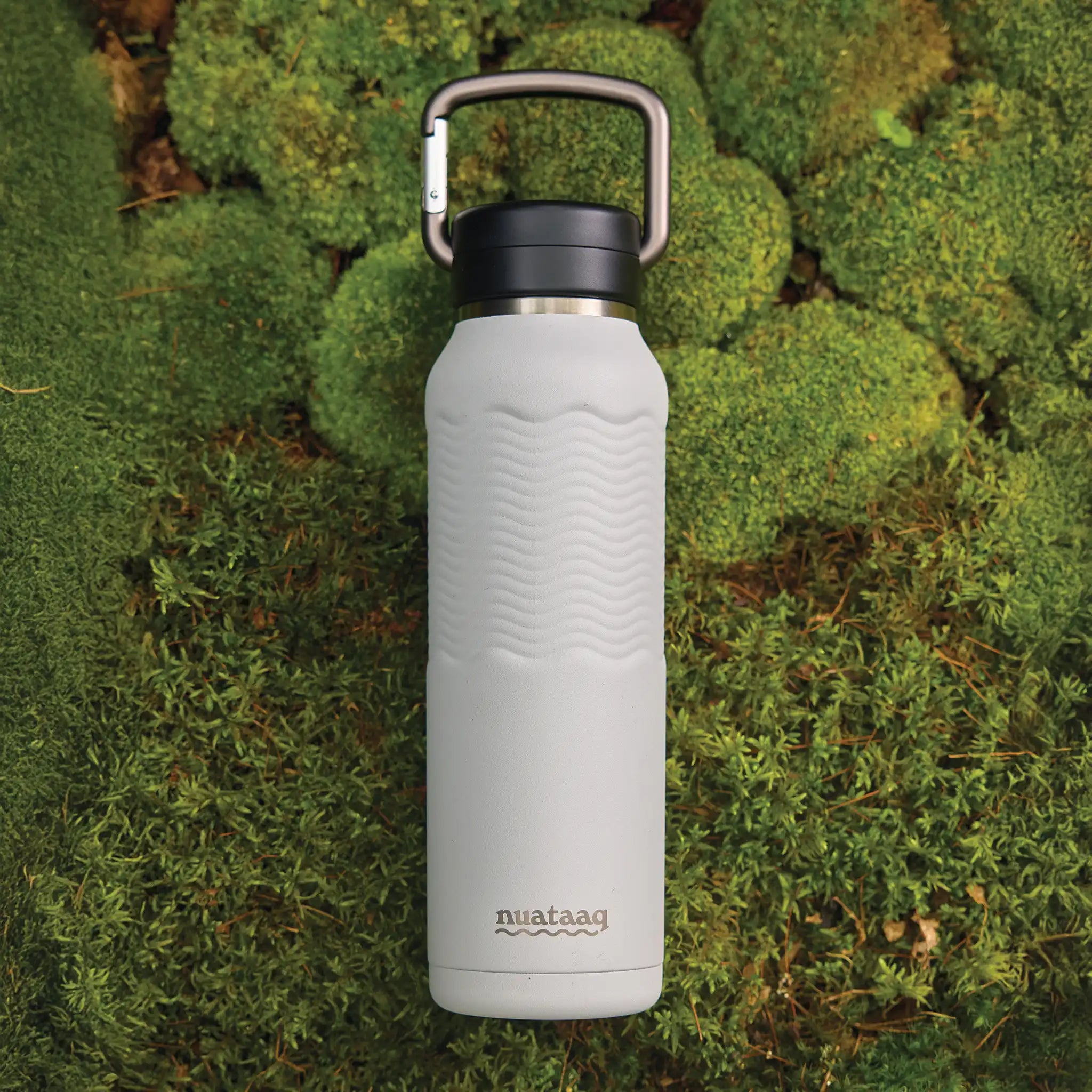 mist gray nuataaq carabiner bottle on a beautiful green moss background