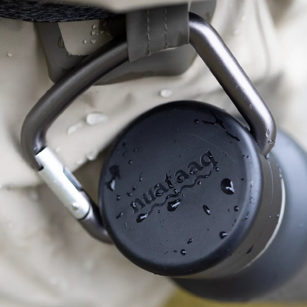 Nuataaq carabiner bottle clipped to the waist belt of a fly fisherman in a river