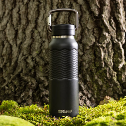 Black insulated water bottle with carabiner against a tree trunk 