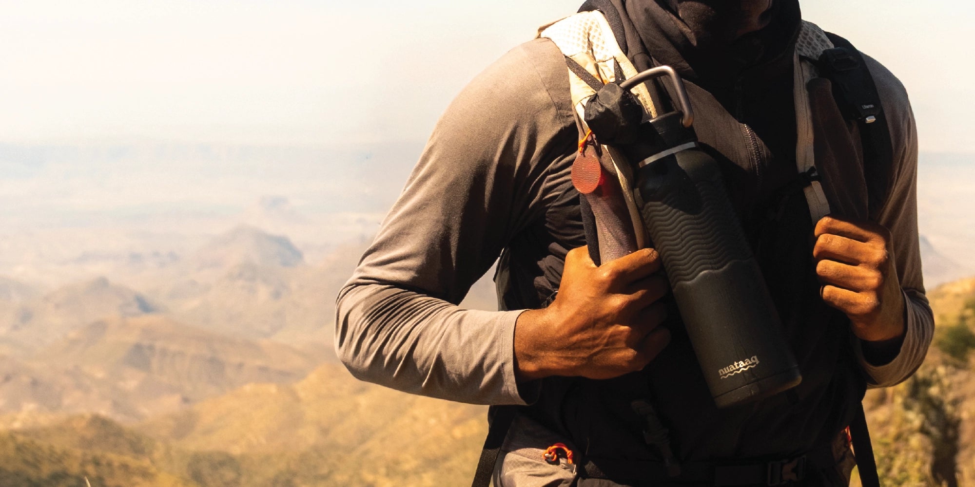 Person holding a black  nuataaq carabiner bottle with a scenic background