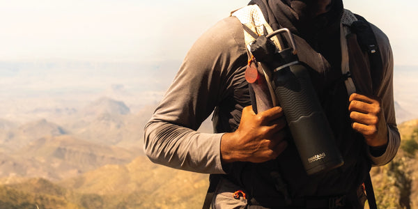 Person holding a black  nuataaq carabiner bottle with a scenic background